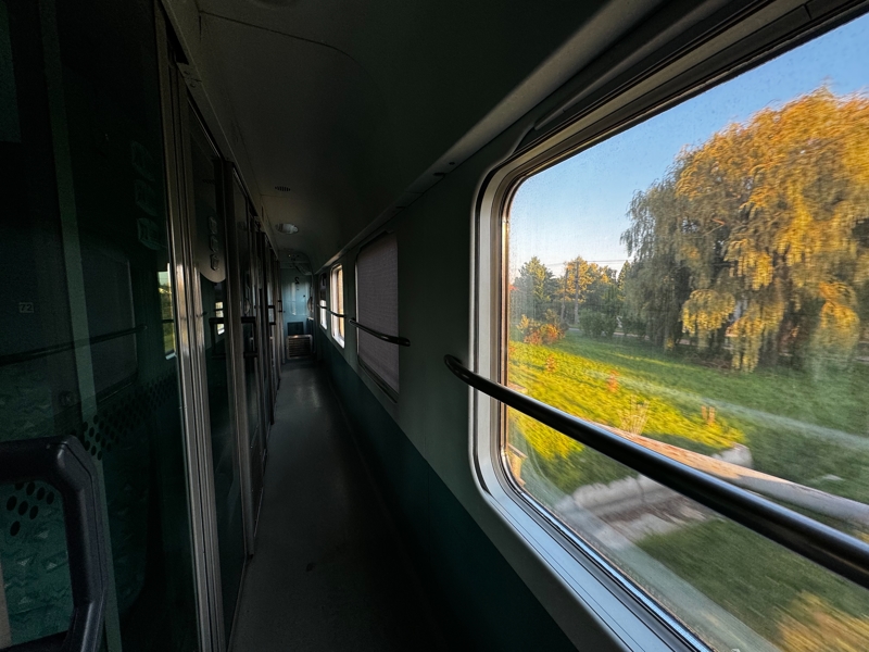 A view through the train window as the sun sets over the countryside A view through the train window as the sun sets over the countryside