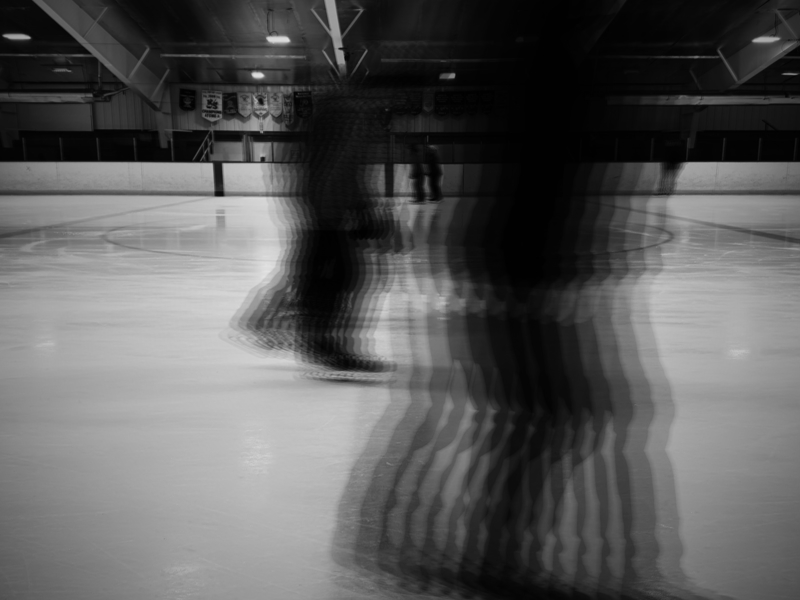 Skaters in an arena are seen blurred as they skate past