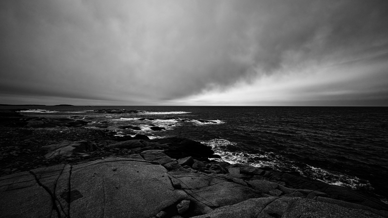 Windy walk along the coast Waves crash against dark rocks as the ocean stretches out to the horizon