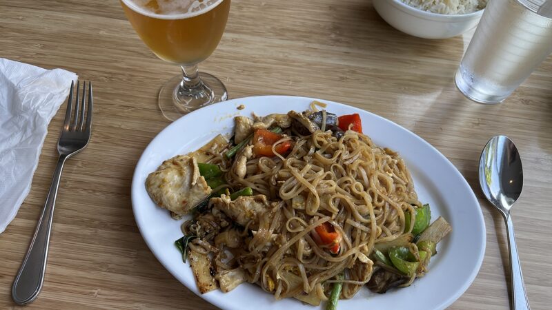 Checked in: Cha Baa Thai Restaurant (Halifax Queen) A large plate of spicy Thai noodles with chicken on a light coloured table and a glass of beer beside.