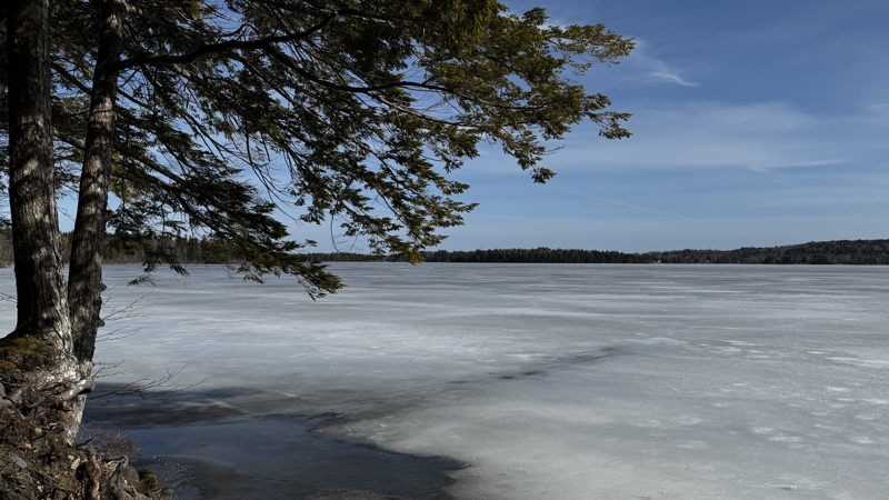 Ice covers a large lake with blue skies above