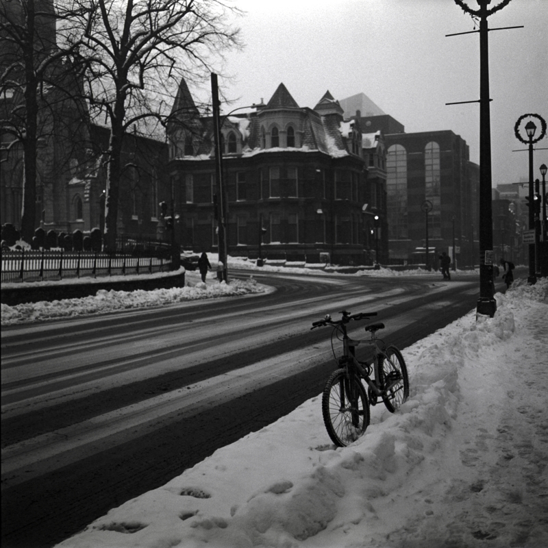 Snowy Christmas Eve Snow gently falls in a city at an intersection with a turreted house on the corner