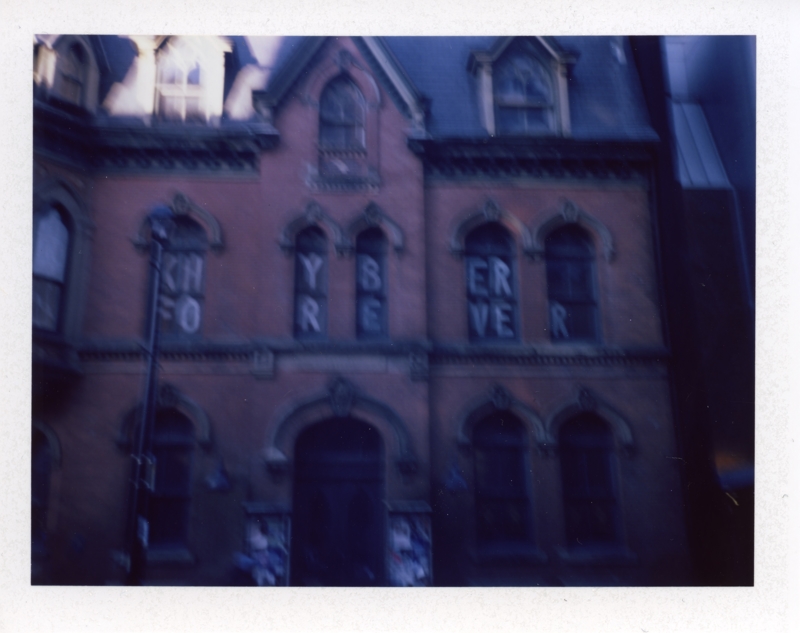 Khyber Forever, October 28, 2024 A slightly blurry photo of a dark brick Victorian building with the words Khyber Forever painted in the windows in white paint
