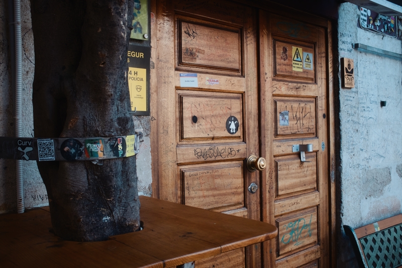 O Velho Eurico, Lisbon, May 2025 Closed brown wooden restaurant doors are covered in scribbled writing and stickers