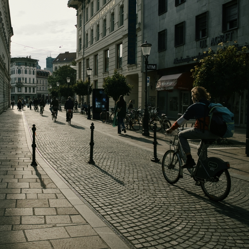 Evening commute, Ljubljana, September, 2024 Cyclists ride along cobbled streets reflecting the sun setting, beautiful old building line the car-free street