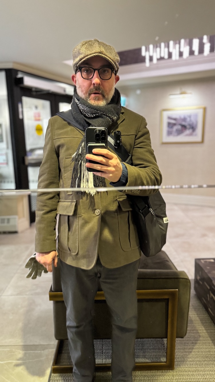 Ready to face the cold Halifax winds Self-portrait of me in a mirrored wall in the lobby of my building wearing a dark green wool coat, black-and-white scarf and a newsboy cap